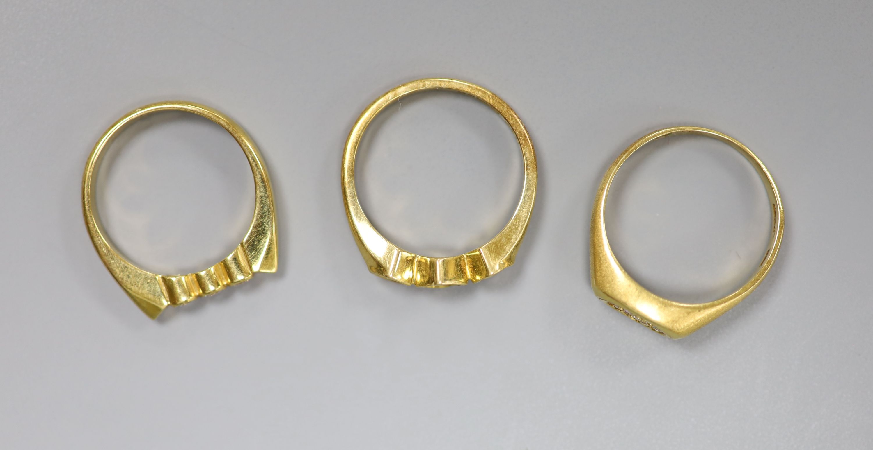 Three assorted modern 18ct gold and diamond set rings, including two three stones and a seven stone diamond chip cluster